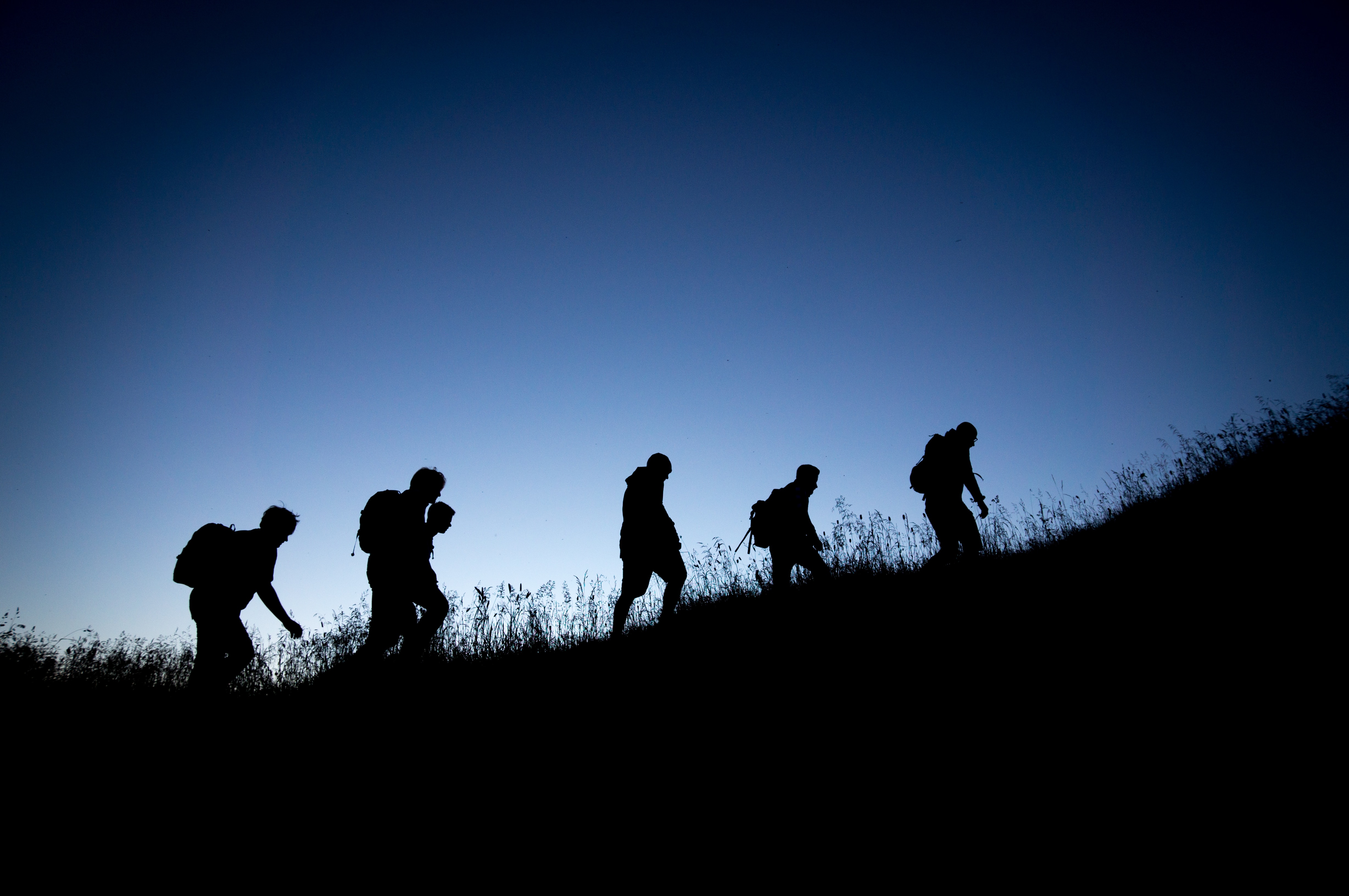 Men ascending a hillside together at dusk
